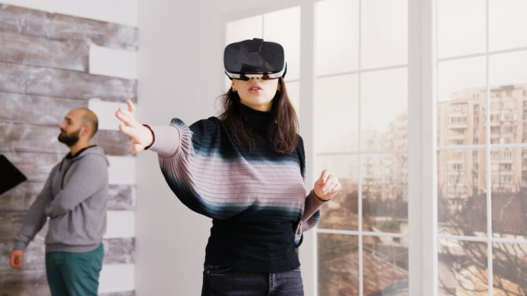 Female Architect Using Virtual Reality Goggles In Empty Apartment